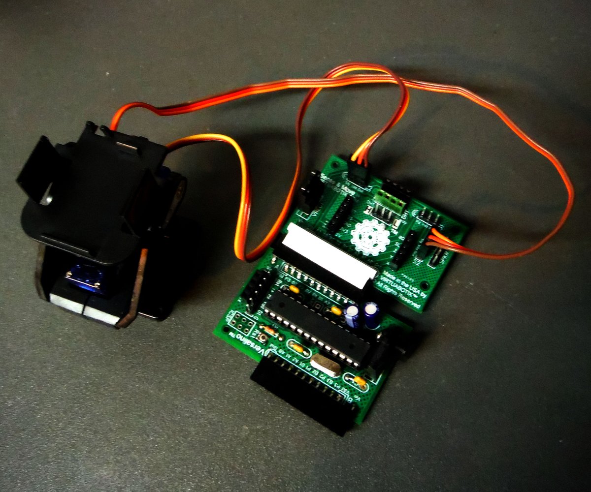 A Versalino Sense & Move board wired to a pan-tilt servo bracket, on a dark surface.
